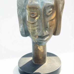 Escultura en bronce titulada Rostro de mujer del artista Vladimir Cora, sobre una base circular en un entorno de galería.